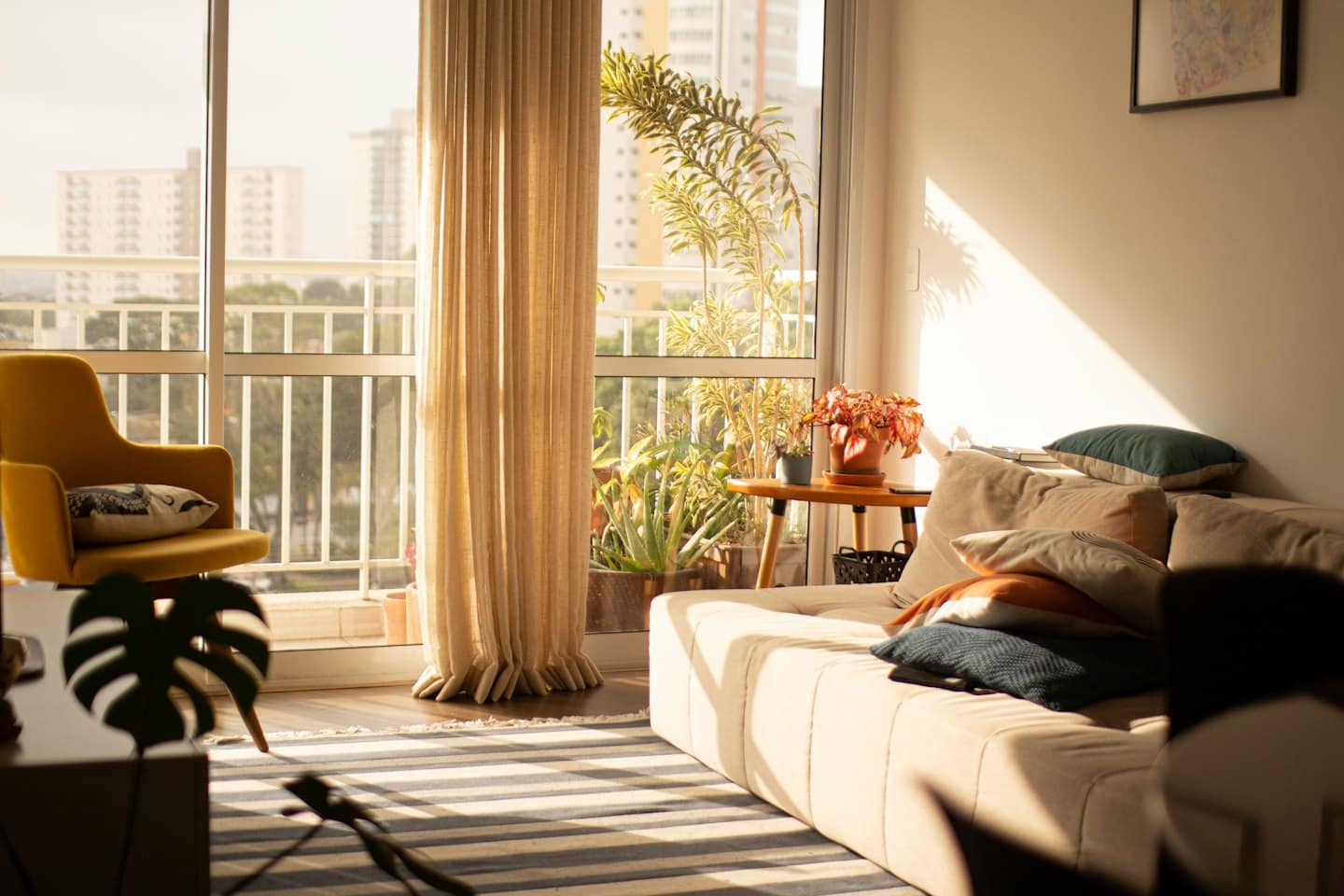 Beige sofa and yellow armchair in sunny living room.