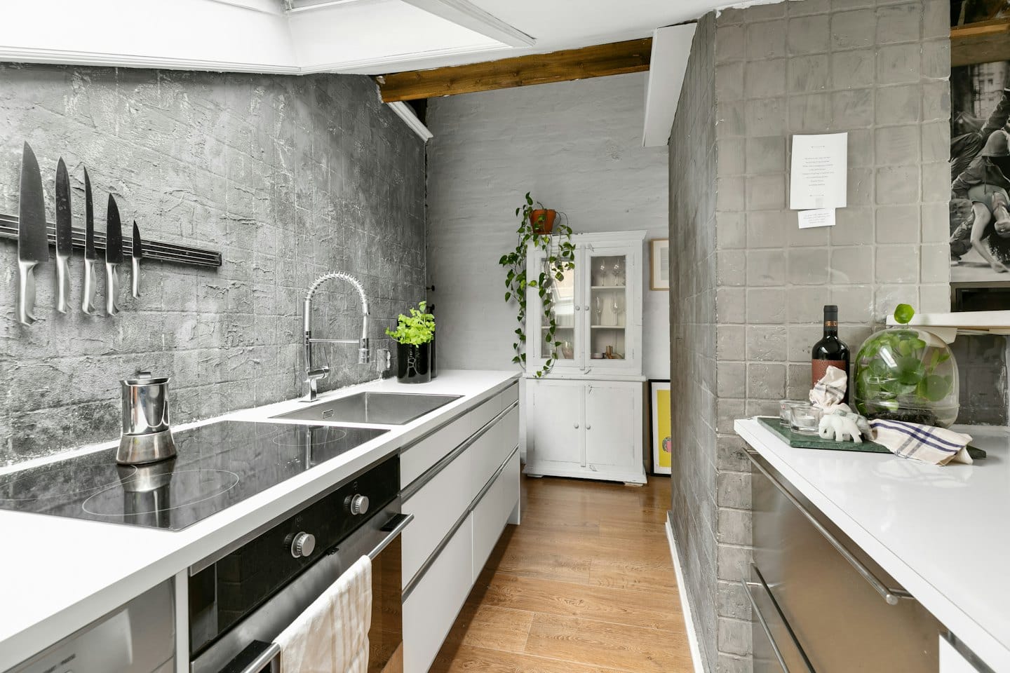 Modern kitchen with white countertops and wooden floors.